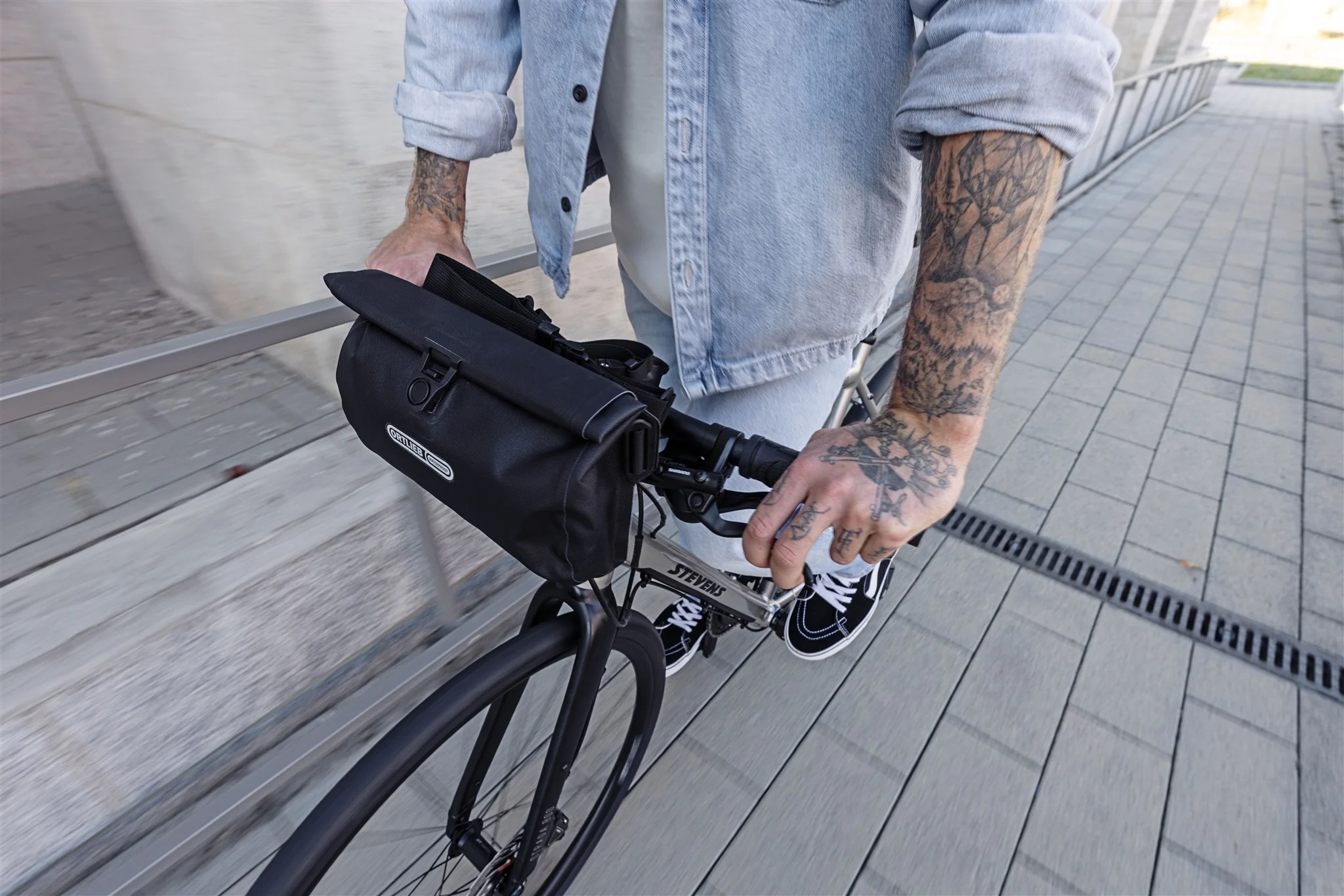 Schwarze ORTLIEB Velo-Sling Flex Lenkertasche mit Rollverschluss und Bar-Lock-System am Fahrrad im Stadtverkehr.